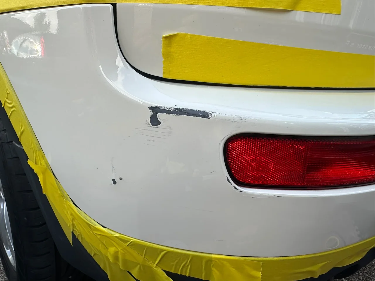 Scuff damage to white vehicle bumper before repair