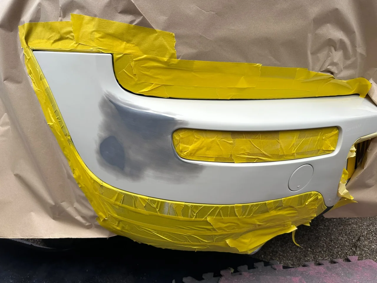 White vehicle bumper undergoing preparation for cosmetic repair